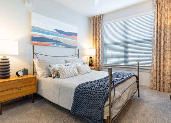 A bedroom with a large bed and a painting on the wall.