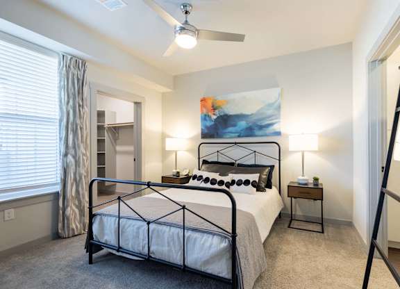 A bedroom with a large bed and a ceiling fan.