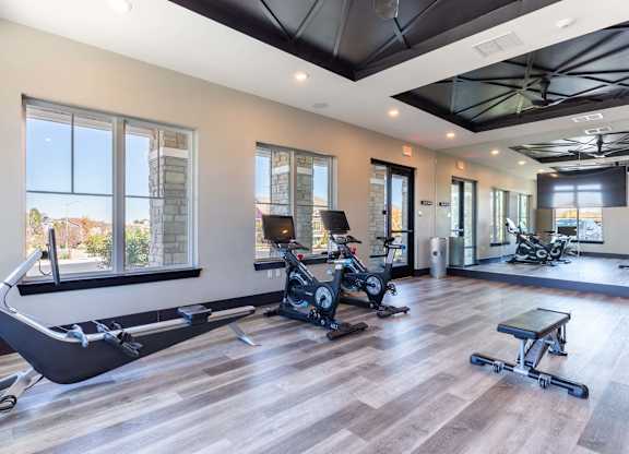 A gym with a rowing machine, treadmill, and weights.