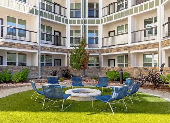 A small garden with a table and chairs in front of apartment buildings.
