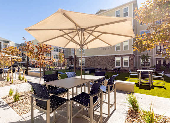 A patio with a table and chairs under an umbrella.