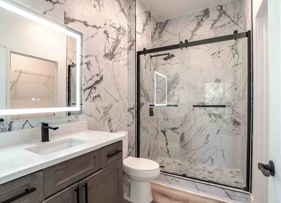 A bathroom with a marble wallpaper and a walk-in shower.