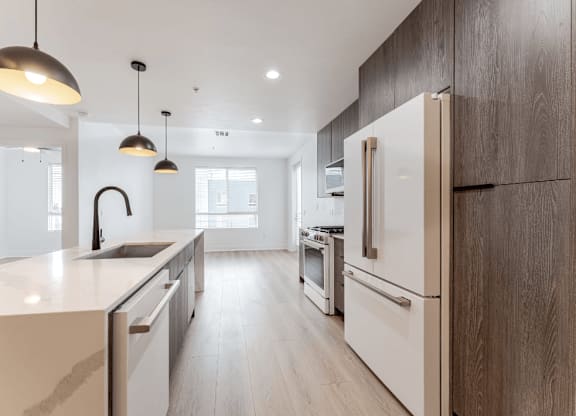 A modern kitchen with a white countertop and wooden cabinets.