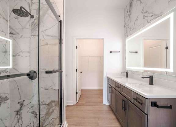A bathroom with a marble shower and a white sink vanity.