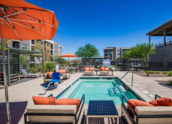 A pool area with orange umbrellas and lounge chairs.
