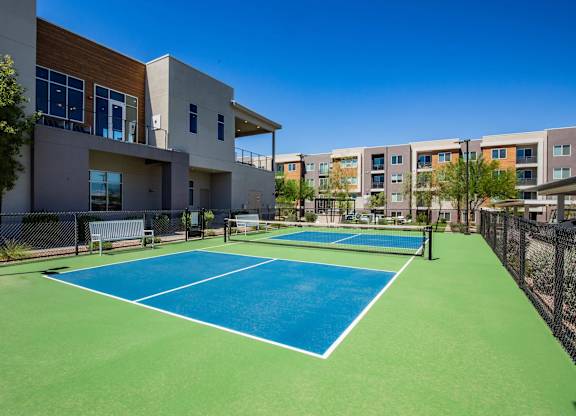 A tennis court is located in front of a building.
