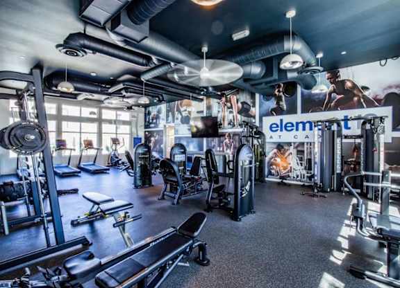 A gym with a variety of equipment including treadmills, weights, and exercise machines.