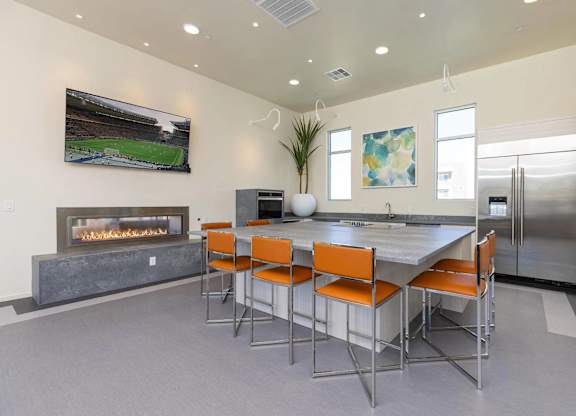 A modern kitchen with a fireplace and a dining table with orange chairs.