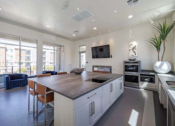 A modern kitchen with a large island and a flat screen TV mounted on the wall.
