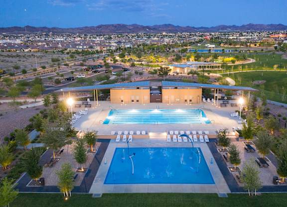 A large swimming pool with a diving board and a building in the background.