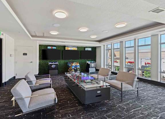 a room with couches and a coffee table with two televisions on the wall and a
