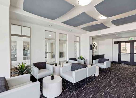 a lobby with white couches and chairs and a black carpet