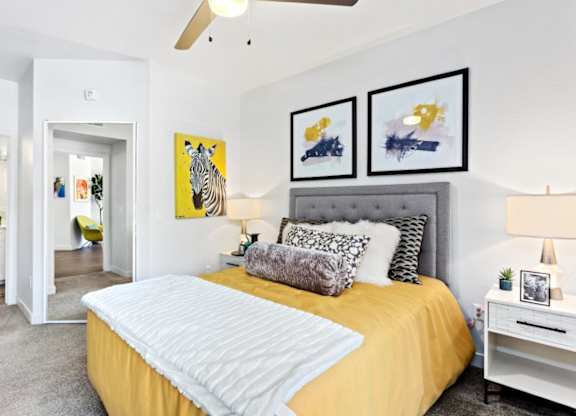 A bedroom with a bed, nightstand, and two framed pictures on the wall.