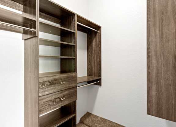 A brown wooden shelf with glass panes is mounted on a white wall.