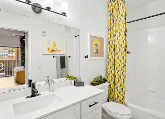 A bathroom with a white sink and a yellow curtain.