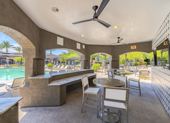 a patio with tables and chairs and a pool in the background