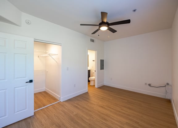 a bedroom with white walls and a ceiling fan