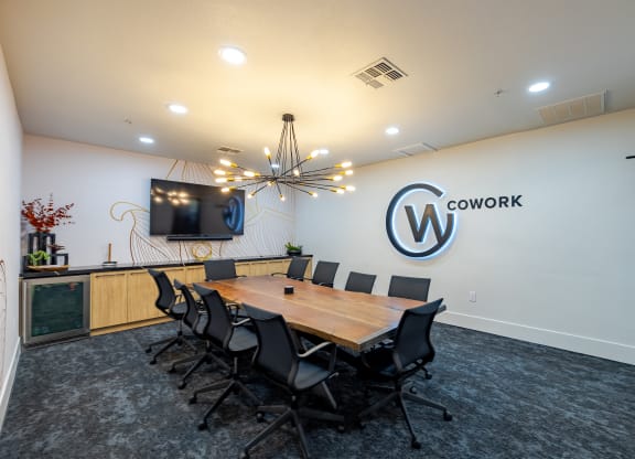 a conference room with a table and chairs and a tv on the wall