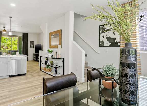 a living room with a glass table and a kitchen