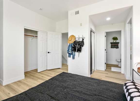 a bedroom with white walls and white closets and a gray rug