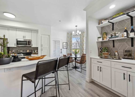 a kitchen with white cabinets and a white counter top with three stools in front of it