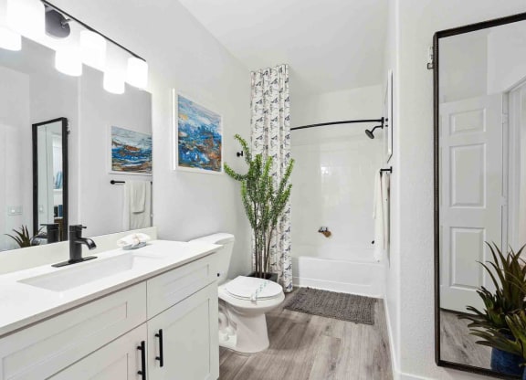a bathroom with a white sink and toilet next to a white bathtub with a shower curtain