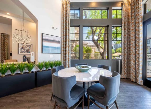 a dining area with a round table and chairs and a large window with a view of the