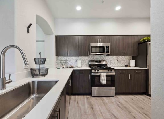 a kitchen with white countertops and dark wood cabinets