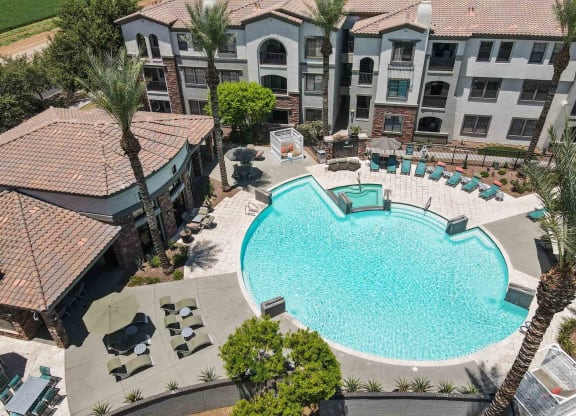 an aerial view of a large swimming pool with lounge chairs and umbrellas in front of