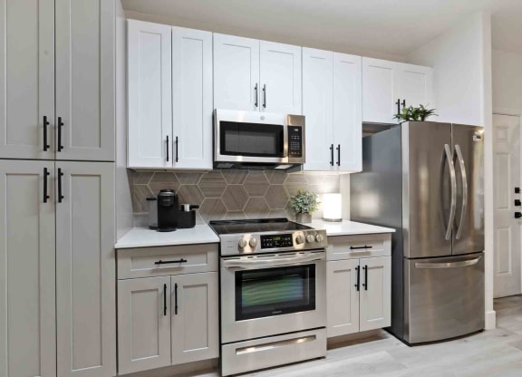A kitchen with gray and white cabinets and stainless appliances at Zone Westgate, townhomes for rent in Glendale, AZ.