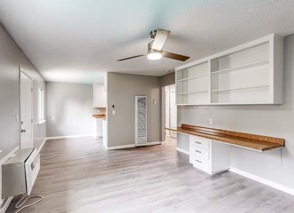 A well-lit, spacious room with a window, a bench, and a ceiling fan at Pennsylvania Place, Davis, CA