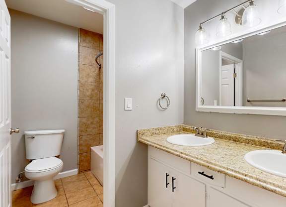 A bathroom with a toilet, sink, and mirror at Pennsylvania Place, Davis, CA