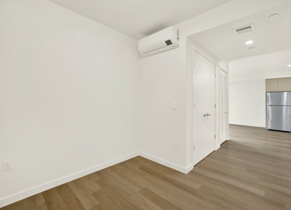 A room with a white wall and a wooden floor at 26FIFTY Apartments, California, 94704