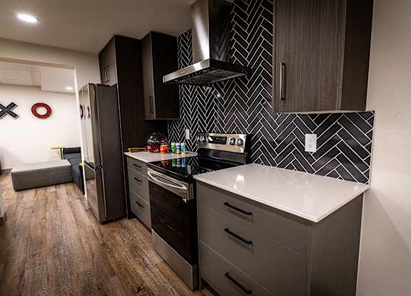 a kitchen with black cabinets and a white counter top and a refrigerator