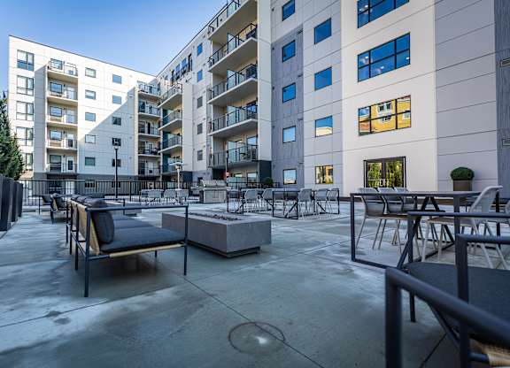 a large patio with tables and chairs in front of an apartment building