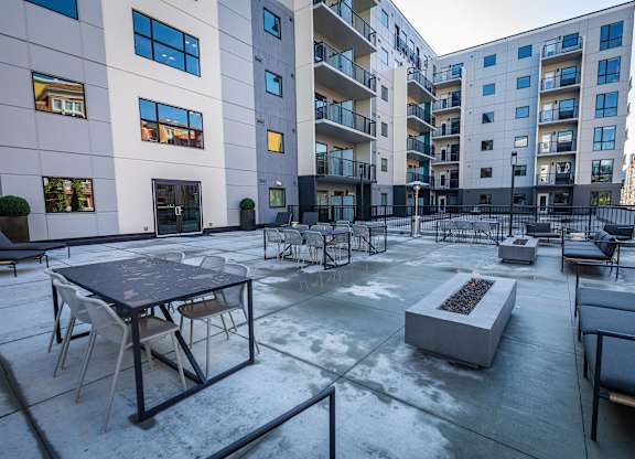 an open courtyard with tables and chairs in front of an apartment building