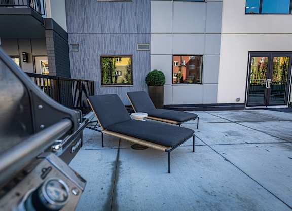 two lounge chairs on the sidewalk in front of a building