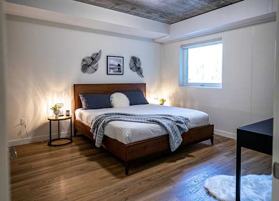 a bedroom with a bed and a grey ceiling and a window