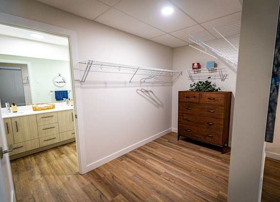 a walk in closet in a bathroom with a mirror and a dresser