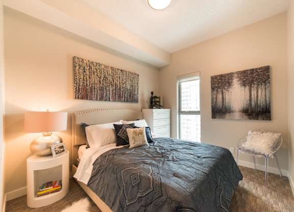 A bedroom with a bed, nightstand, and two pictures on the wall.