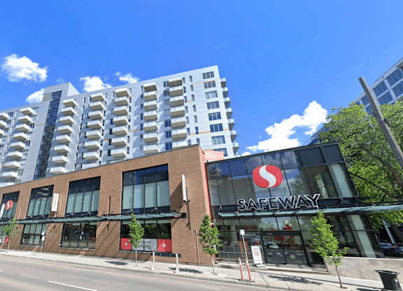 A Safeway store is located in front of a tall building.