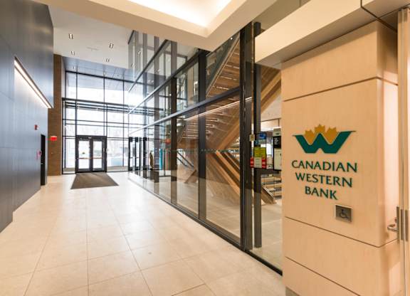 The lobby of the Canadian Western Bank building features a staircase and glass walls.