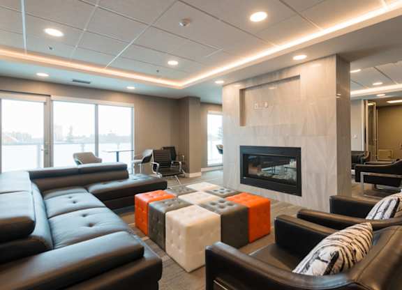 A modern living room with black leather furniture and a fireplace.