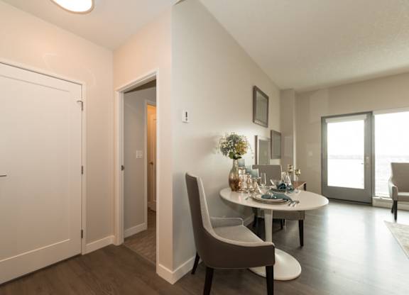 A dining room with a table set for two and a couch.