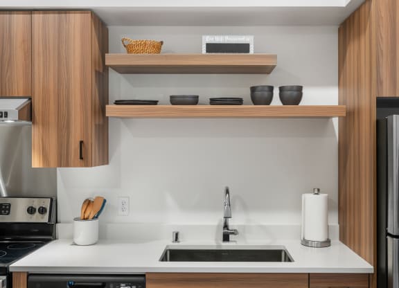a kitchen with a sink and a refrigerator and wooden cabinets