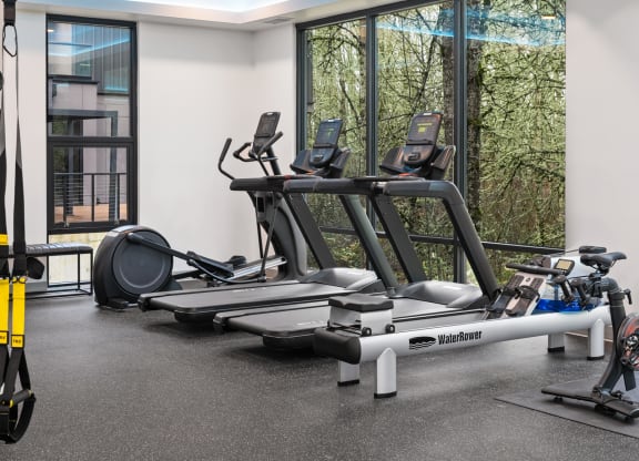 a gym with treadmills and other exercise equipment in a building with windows