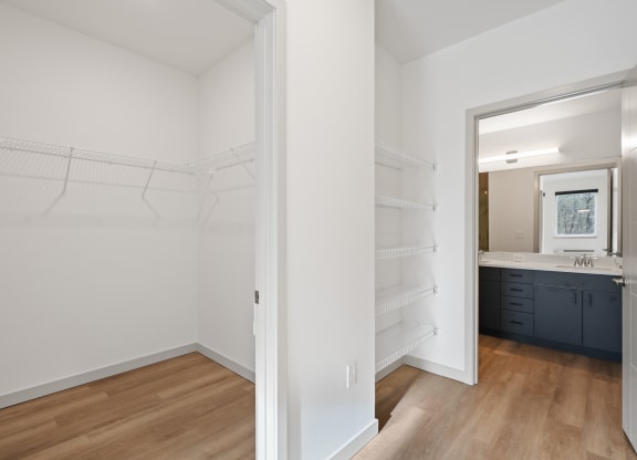 a bedroom with a closet and a bathroom with a sink and a mirror