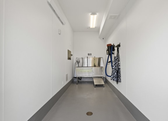 a long white hallway with white walls and a metal cart with hoses in it