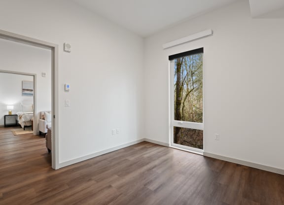 a living room with white walls and a large window and wooden floors