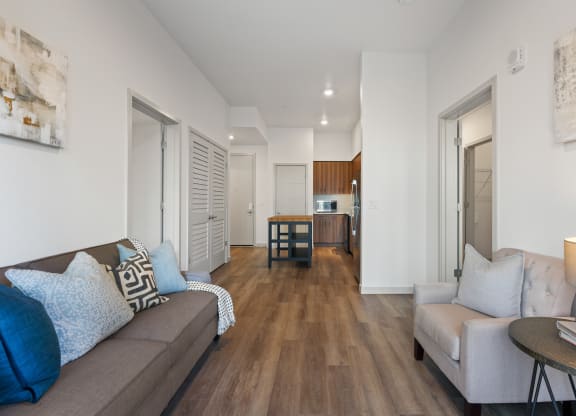 a living room with a couch and a table and a kitchen in the distance